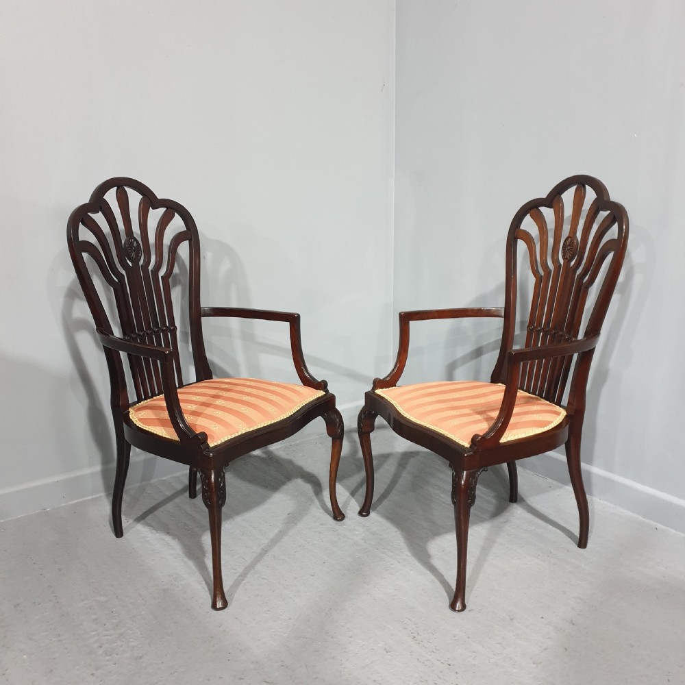 A pair of carved mahogany elbow chairs featuring openwork fan backs, swept armrests, terracotta striped upholstered seats, and cabriole front legs. View X
