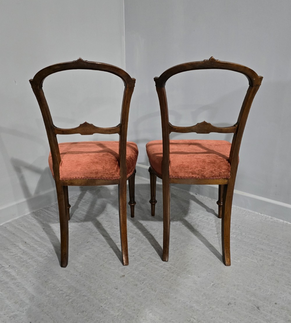 A pair of Victorian mahogany side chairs with openwork carved backs, turned front legs, and terracotta velvet seats. View V