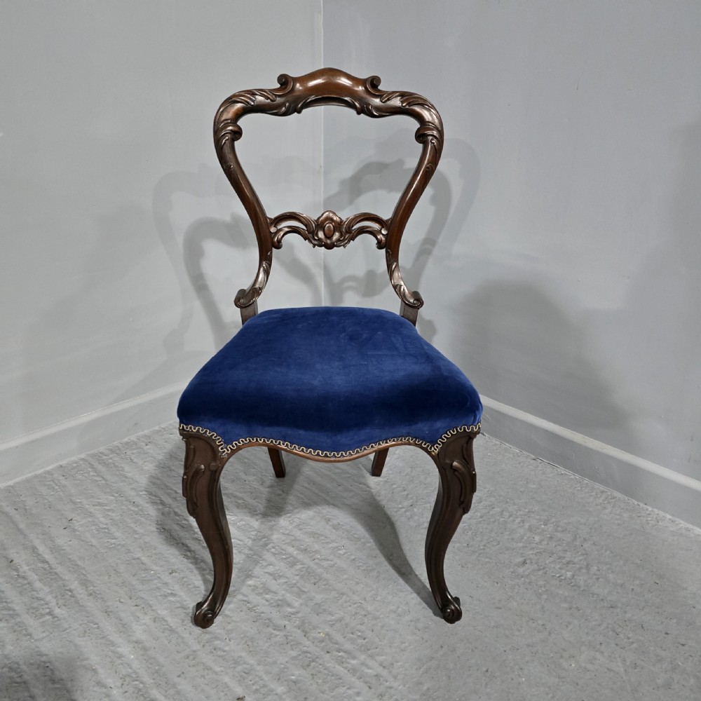 A Victorian rosewood side chair featuring an openwork balloon back, blue velvet upholstered seat, and cabriole legs.