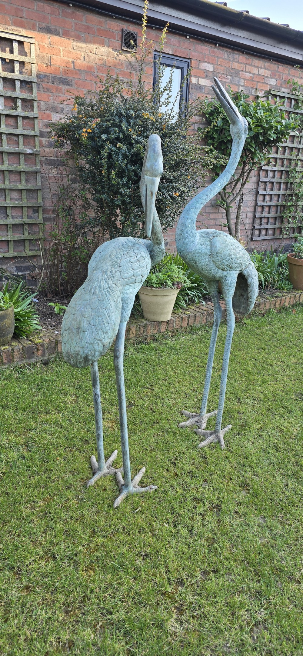 A pair of large cast metal crane statues featuring a weathered verdigris green finish and detailed feather texturing. View IV