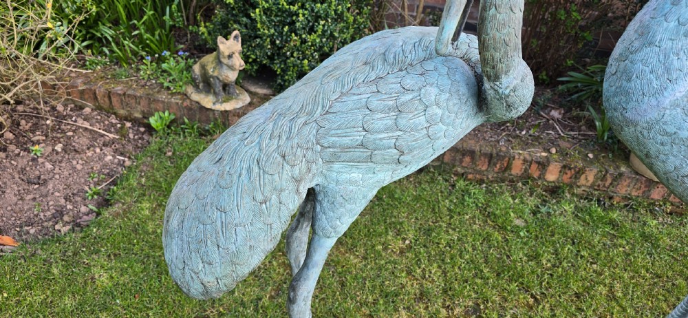 A pair of large cast metal crane statues featuring a weathered verdigris green finish and detailed feather texturing. View V