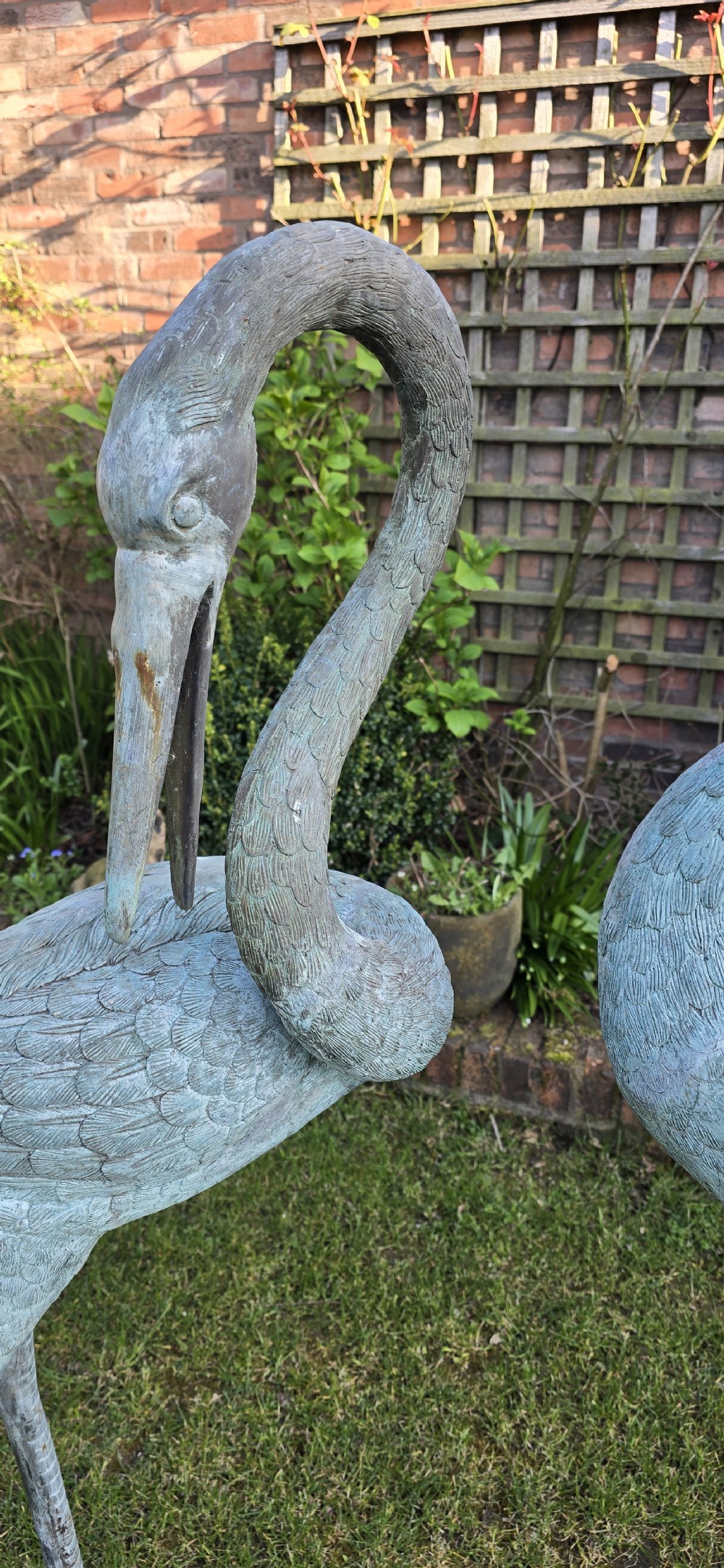 A pair of large cast metal crane statues featuring a weathered verdigris green finish and detailed feather texturing. View VI