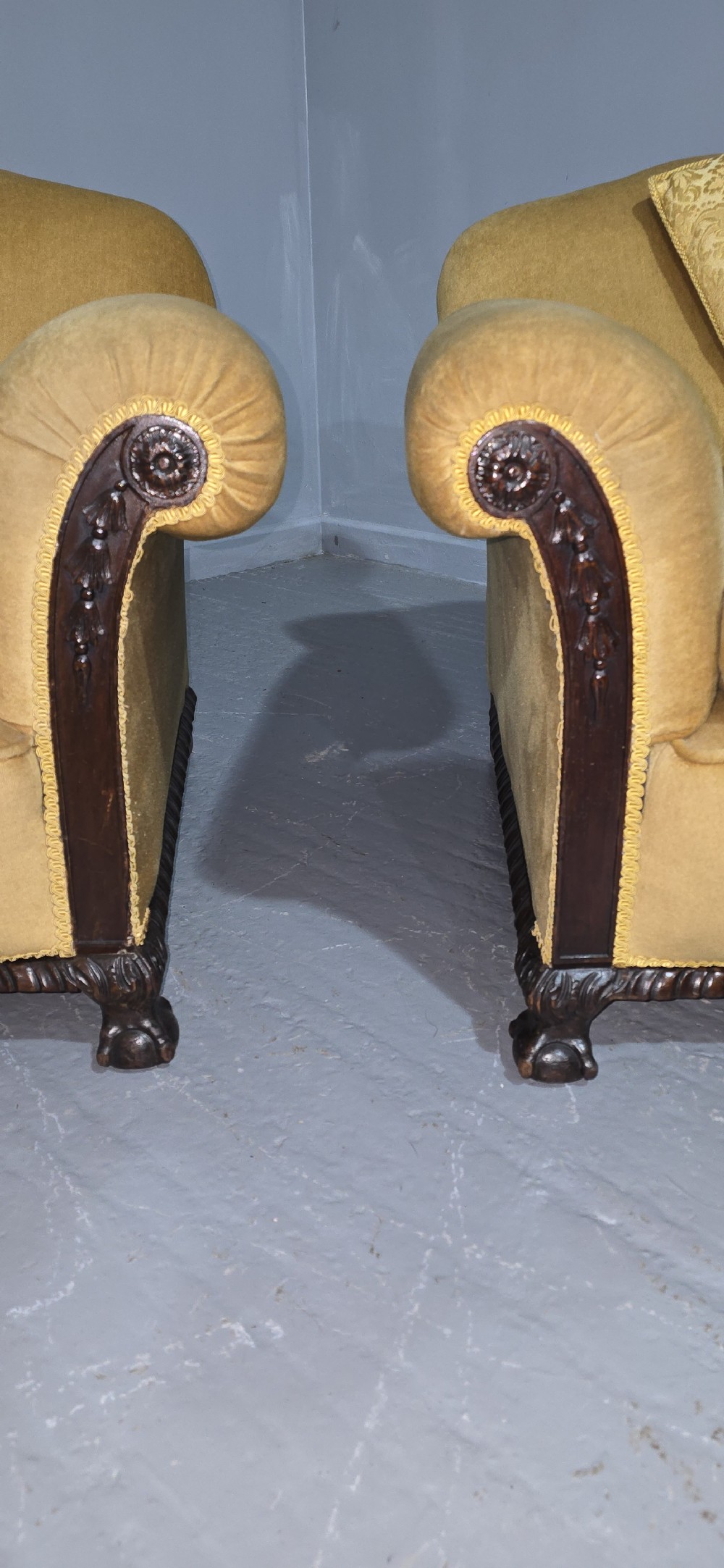 A pair of yellow velvet upholstered club chairs featuring carved dark timber trim along the front arms and base. View II