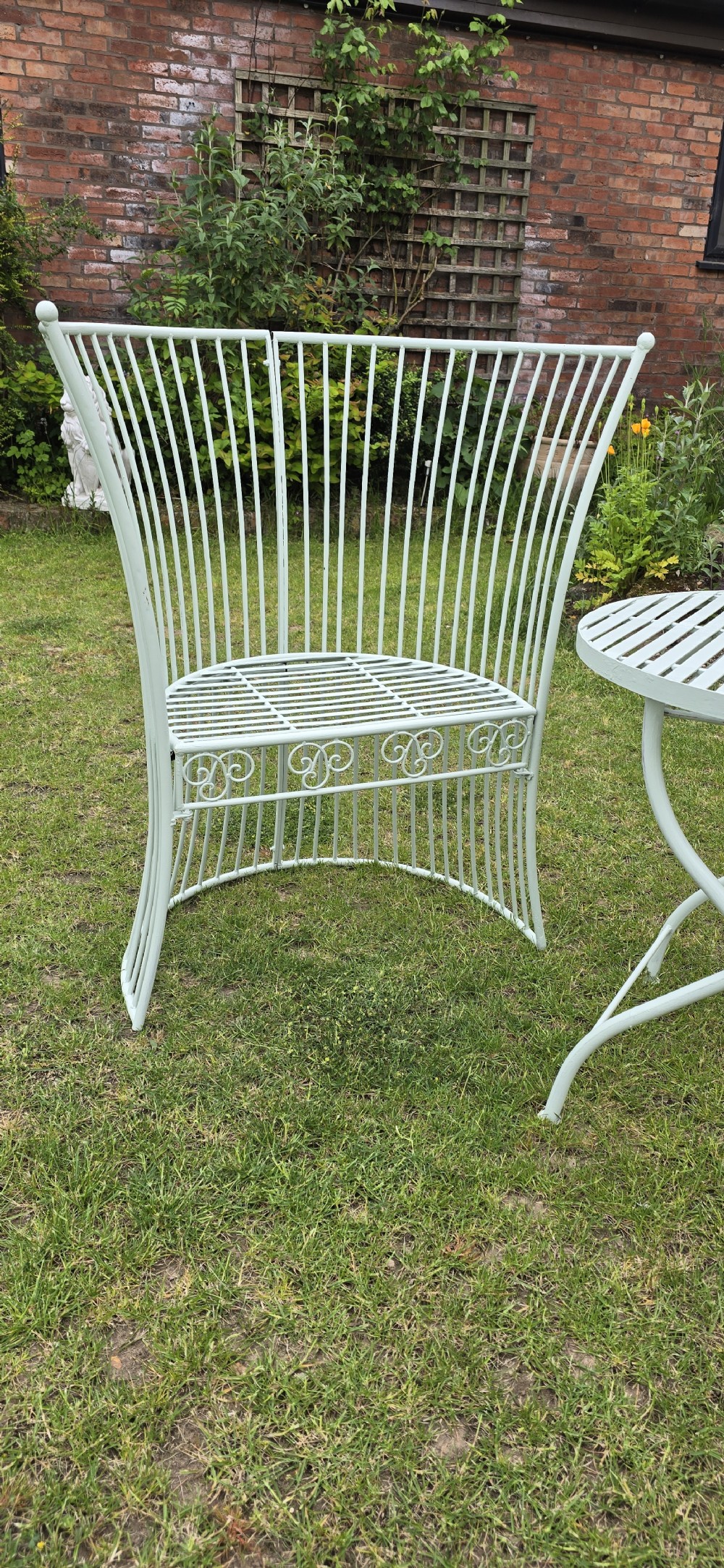 A three-piece pale green painted iron patio set featuring two high fan-back slatted armchairs and a small round folding bistro table. View III