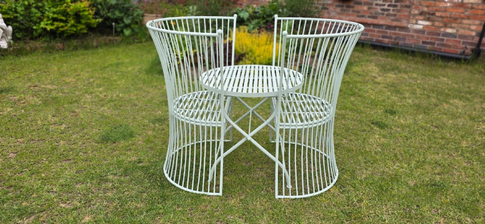 A three-piece pale green painted iron patio set featuring two high fan-back slatted armchairs and a small round folding bistro table. View VIII