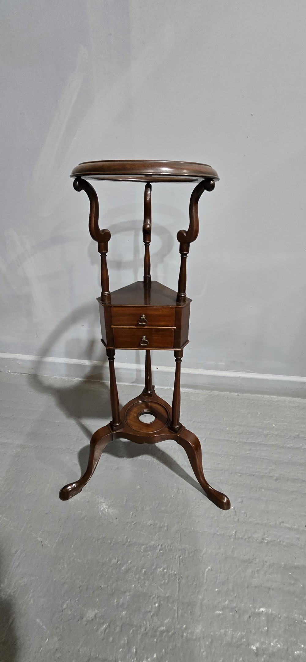 An eighteenth-century Georgian mahogany wig stand featuring a circular top ring, curved upright supports, a central triangular drawer section, and a tripod base with pad feet. View II