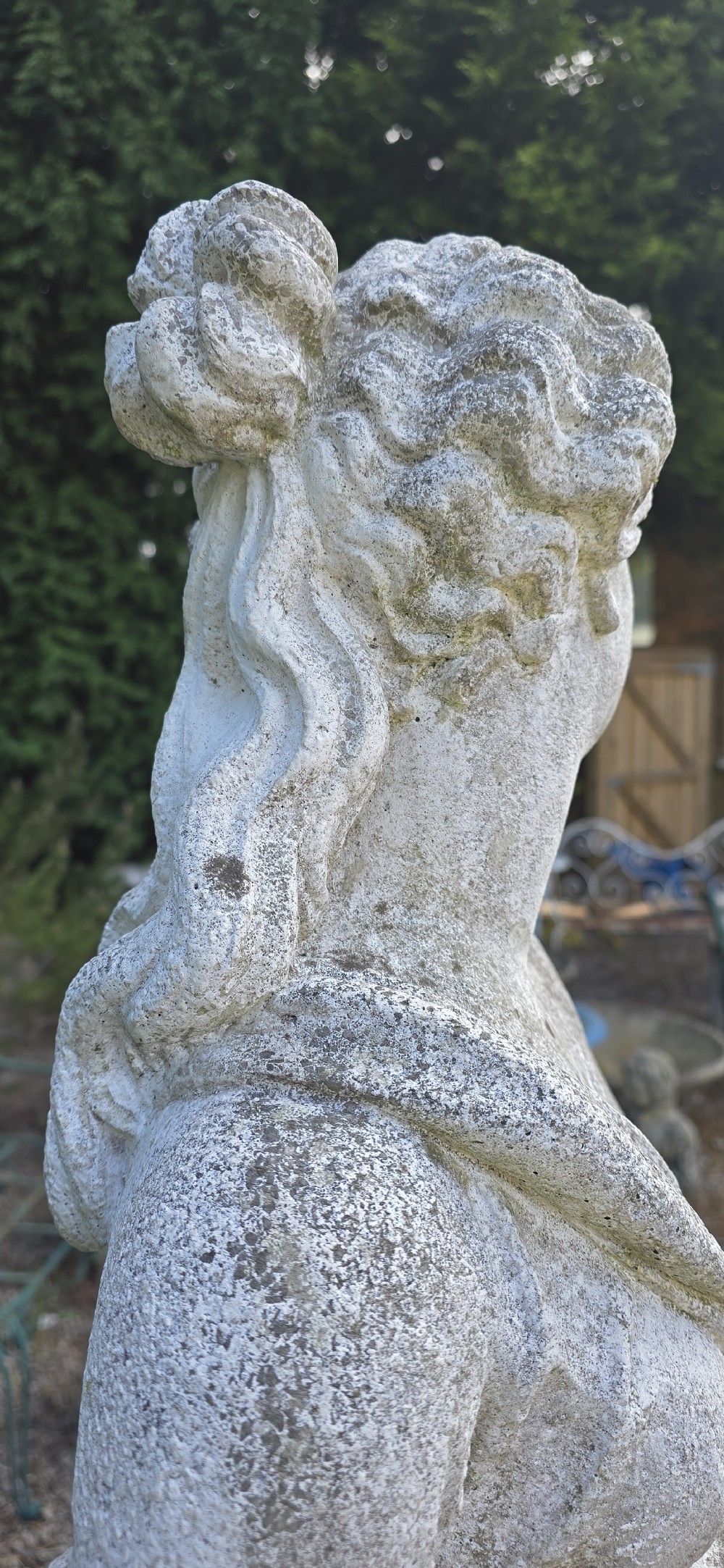A full-length cast stone statue of a classical draped female figure standing atop a square carved plinth base. View VII