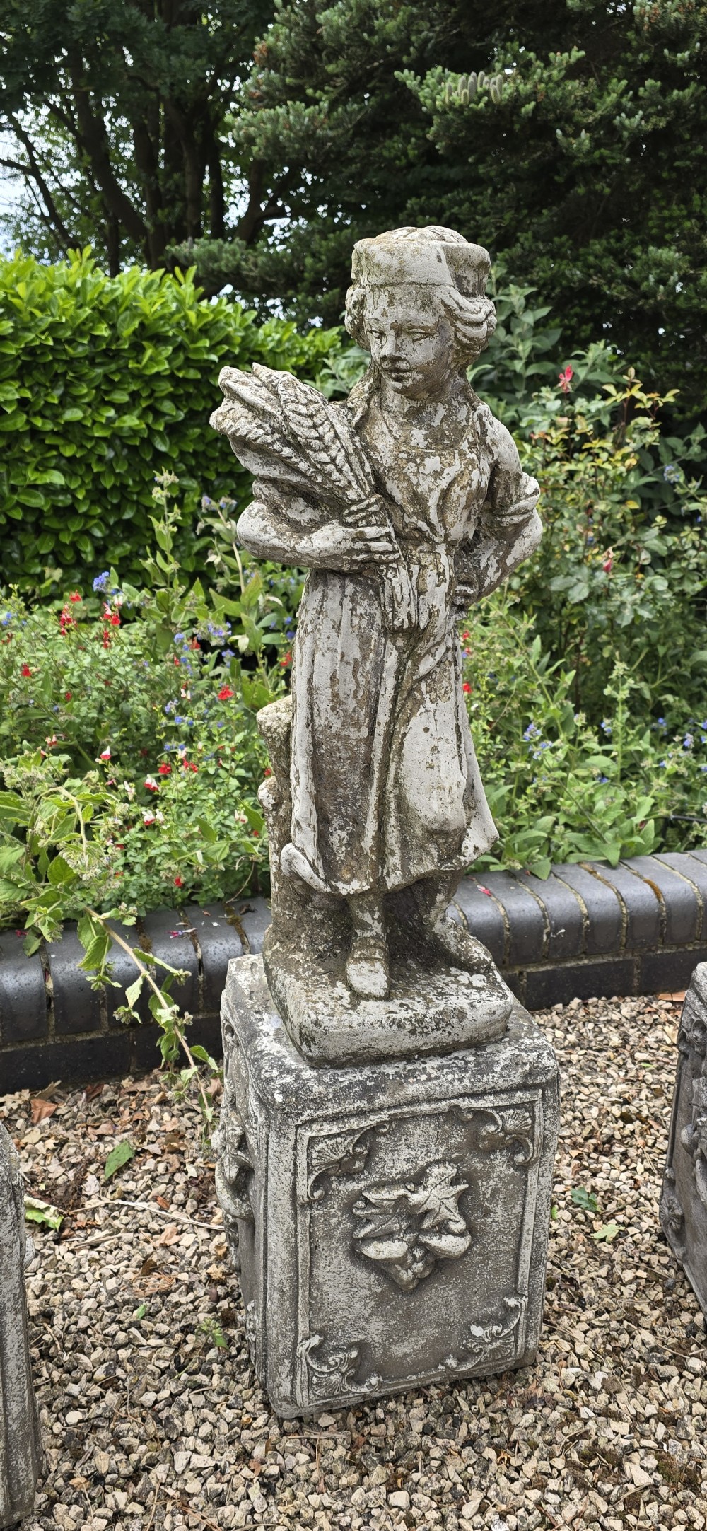 A set of four weathered grey cast stone statues representing the Four Seasons standing on matching square relief-decorated pedestals. View V
