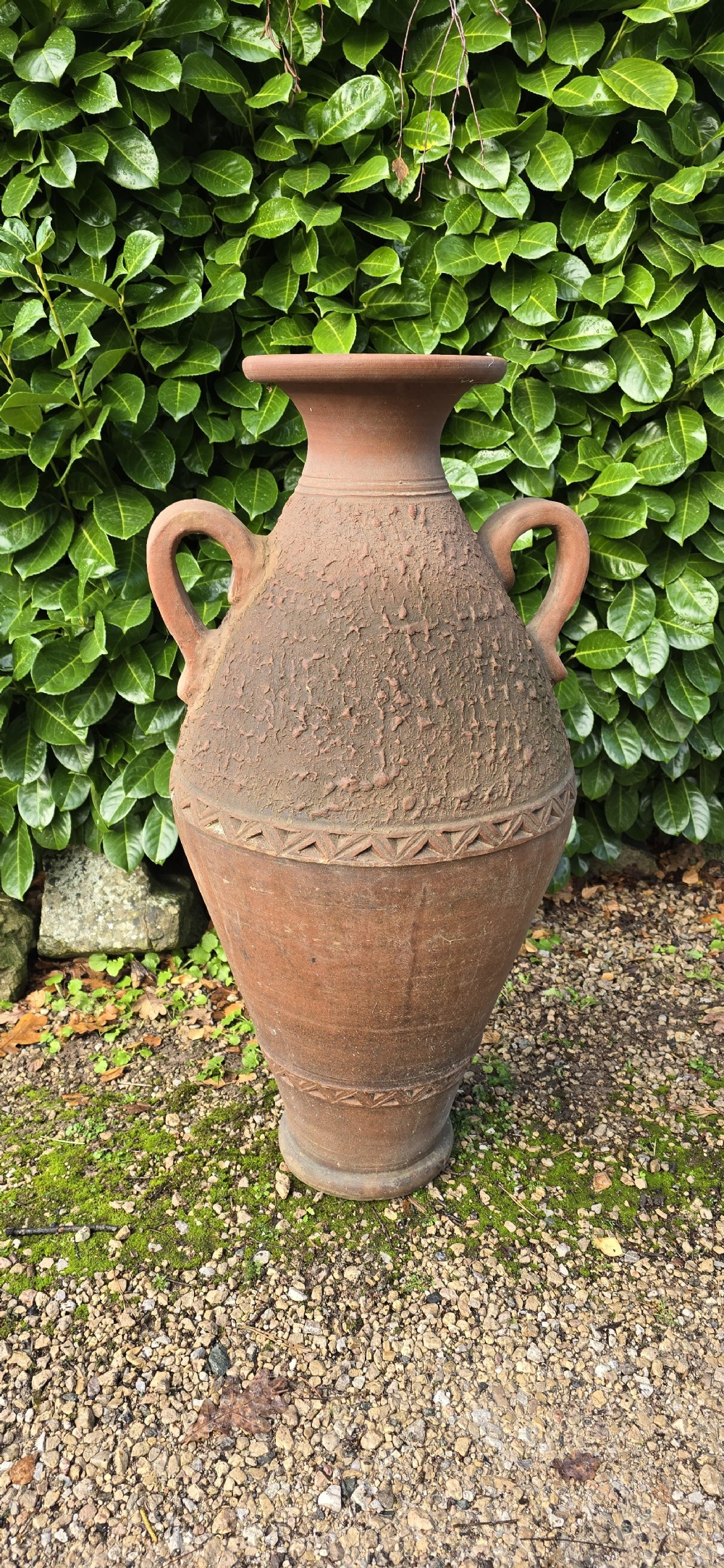A large terracotta oil jar with two side handles, a textured upper body, and incised geometric patterning. View II