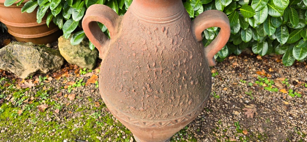 A large terracotta oil jar with two side handles, a textured upper body, and incised geometric patterning. View V