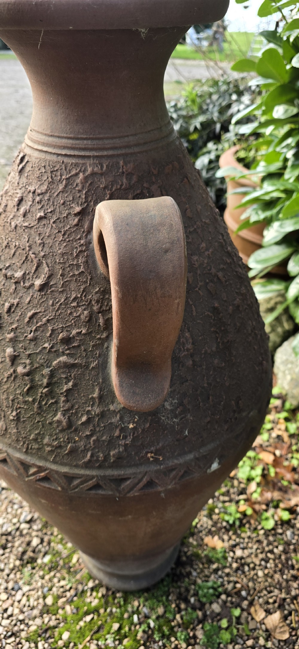 A large terracotta oil jar with two side handles, a textured upper body, and incised geometric patterning. View VI