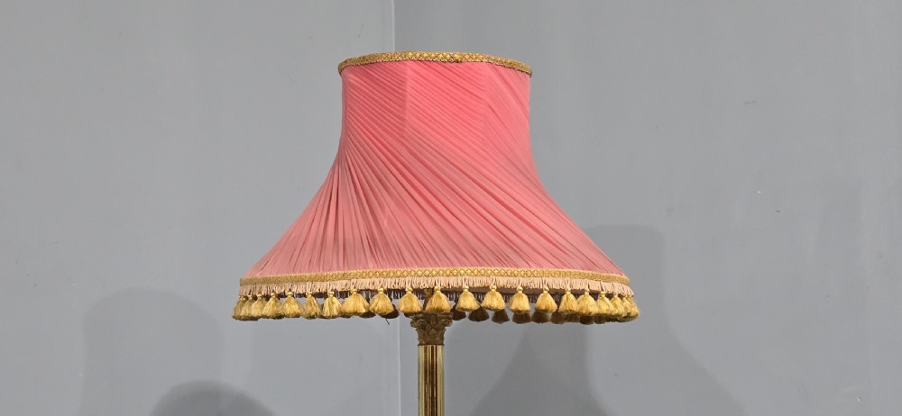 A solid brass standard lamp featuring a fluted Corinthian column stem, stepped square base on paw feet, and a pleated pink fabric shade with tassel fringe. View VII