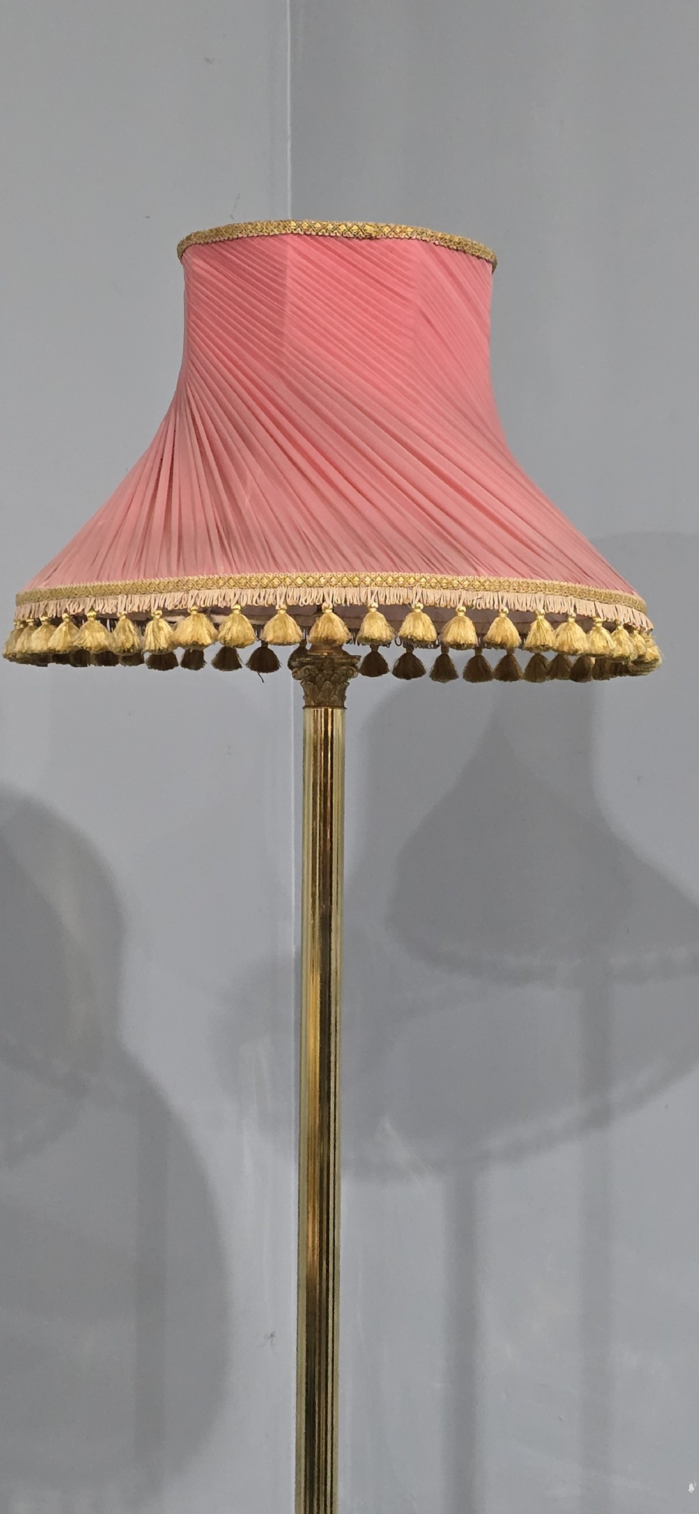 A solid brass standard lamp featuring a fluted Corinthian column stem, stepped square base on paw feet, and a pleated pink fabric shade with tassel fringe. View VIII