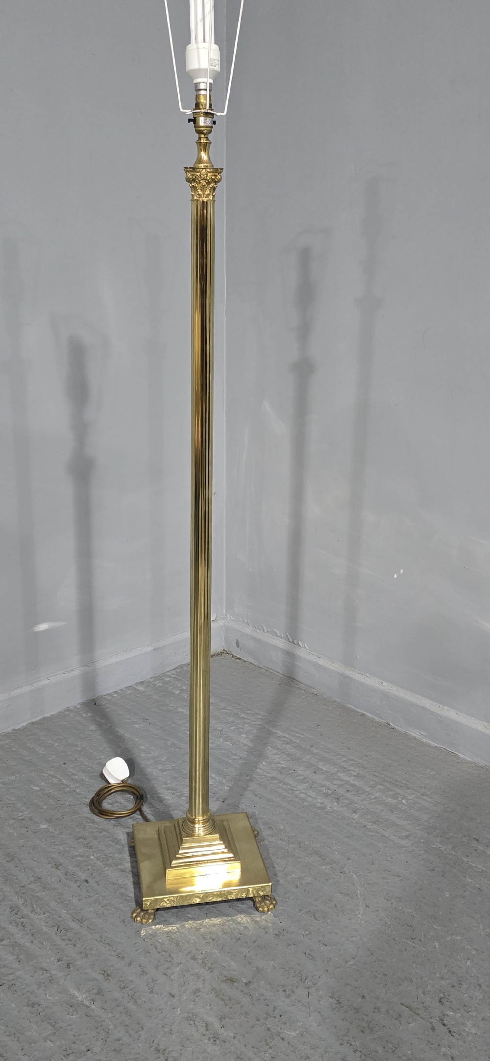 A solid brass standard lamp featuring a fluted Corinthian column stem, stepped square base on paw feet, and a pleated pink fabric shade with tassel fringe. View X