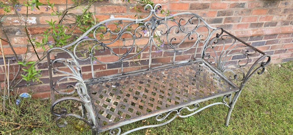 A French metal garden bench featuring a weathered grey-green painted finish, decorative scrollwork backrest, rolled arms, and a lattice seat. View IV