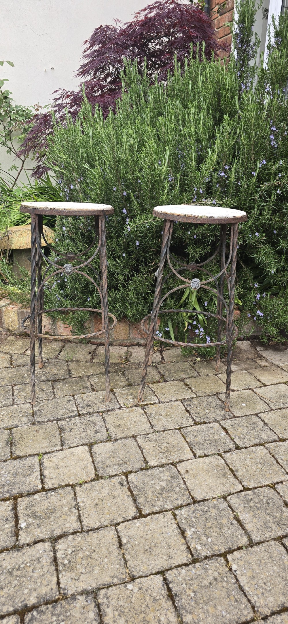 A pair of tall wrought iron plant stands with circular stone tops, twisted legs, and central lion mask medallion details. View III