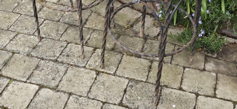 A pair of tall wrought iron plant stands with circular stone tops, twisted legs, and central lion mask medallion details. View IX