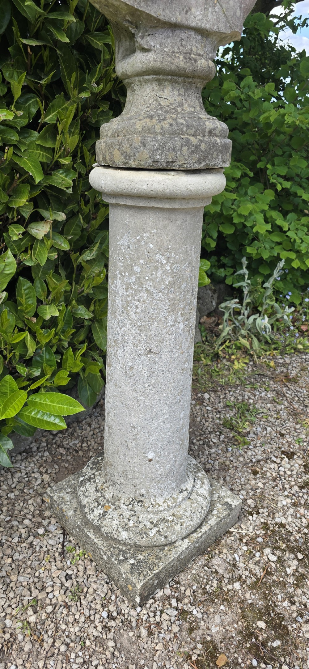 A weathered stone bust of Apollo set atop a cylindrical column pedestal with a square base. View VI