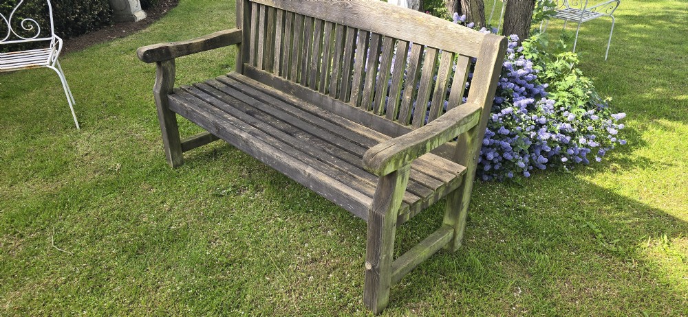A weathered silver-grey teak garden bench featuring a slatted backrest, slatted seat, wide armrests, and straight post legs. View V