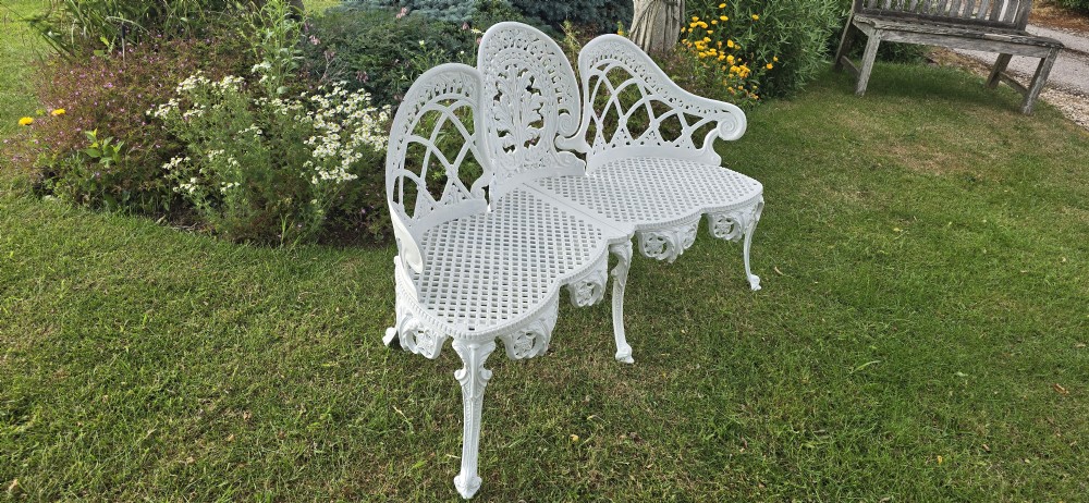 A refurbished white cast metal garden bench featuring an ornate lattice seat, three-part curved backrest with foliage motifs, and decorative legs. View VI
