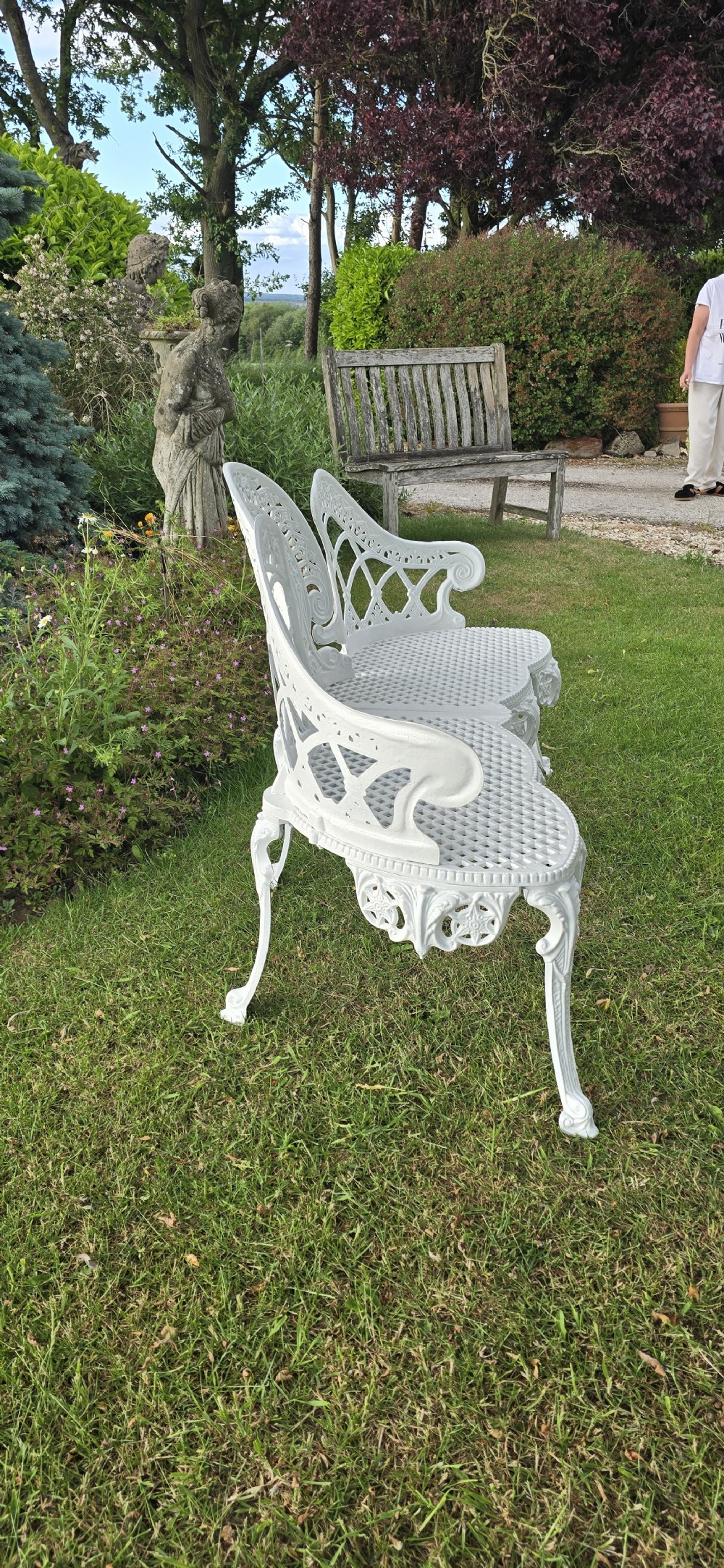 A refurbished white cast metal garden bench featuring an ornate lattice seat, three-part curved backrest with foliage motifs, and decorative legs. View VII