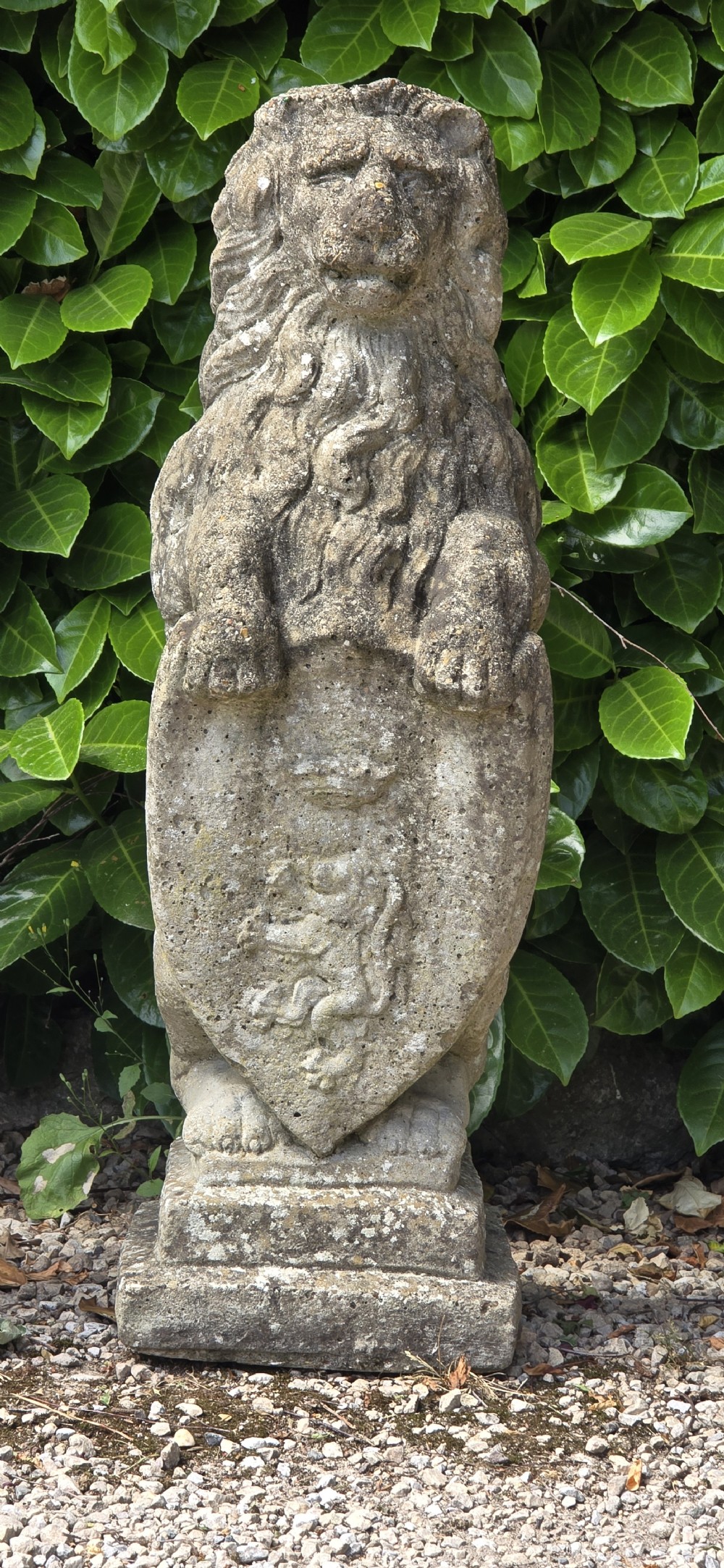 A pair of weathered grey stone garden statues depicting standing lions holding heraldic shields on rectangular bases. View IV