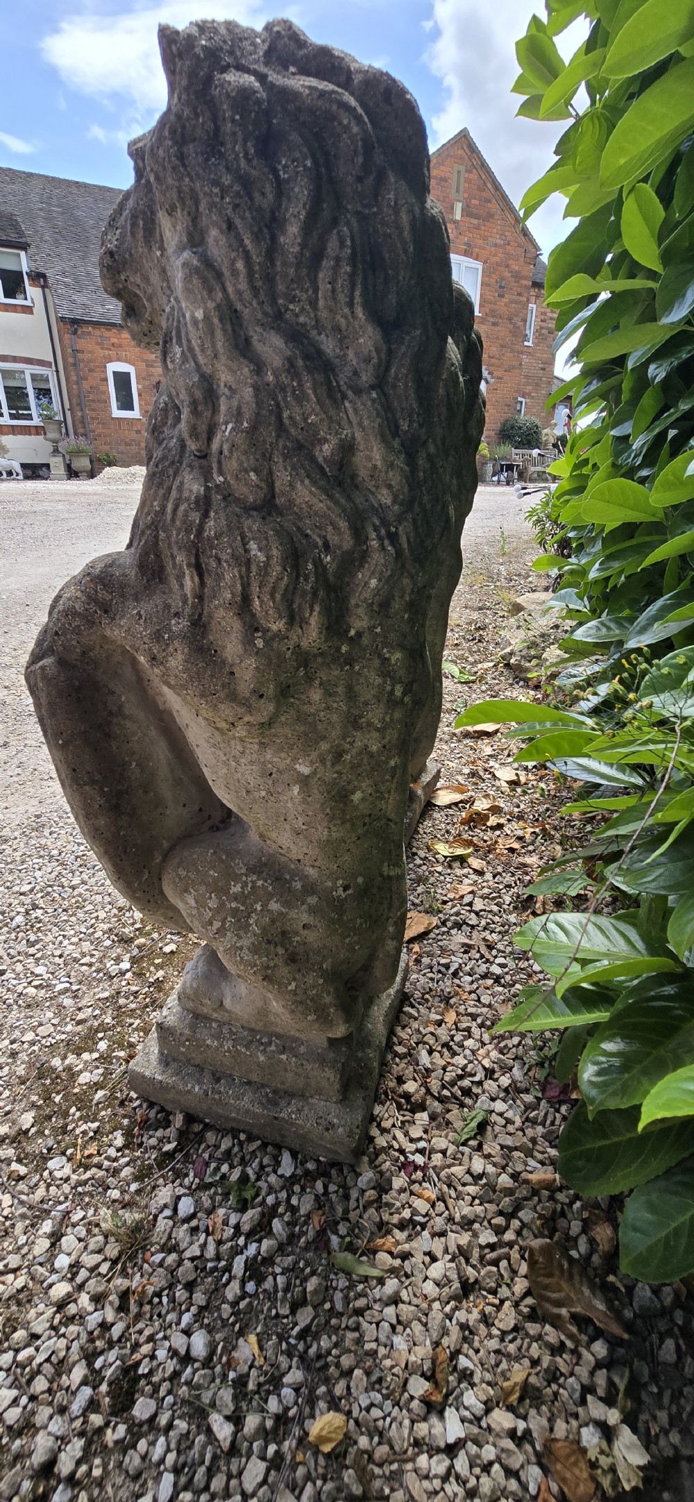 A pair of weathered grey stone garden statues depicting standing lions holding heraldic shields on rectangular bases. View VII