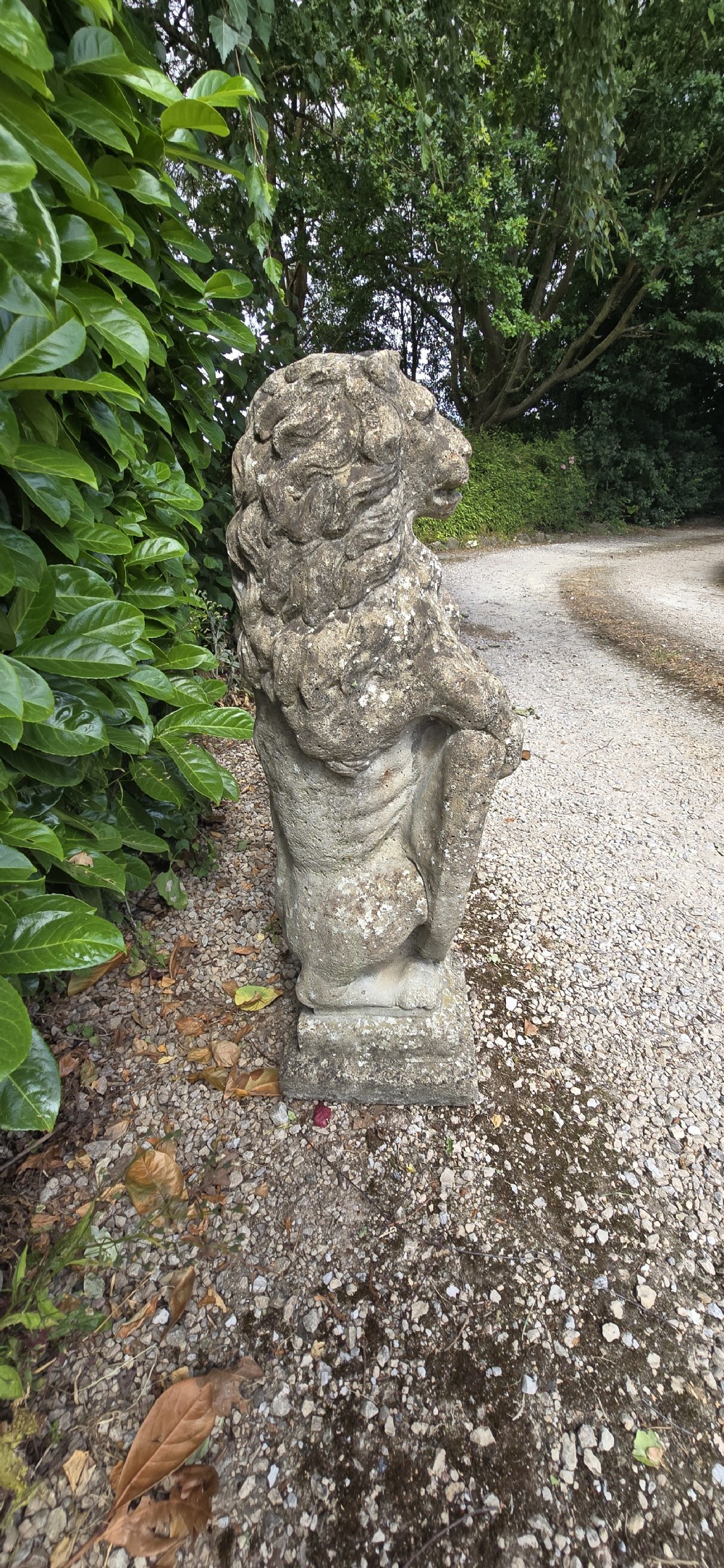 A pair of weathered grey stone garden statues depicting standing lions holding heraldic shields on rectangular bases. View VIII