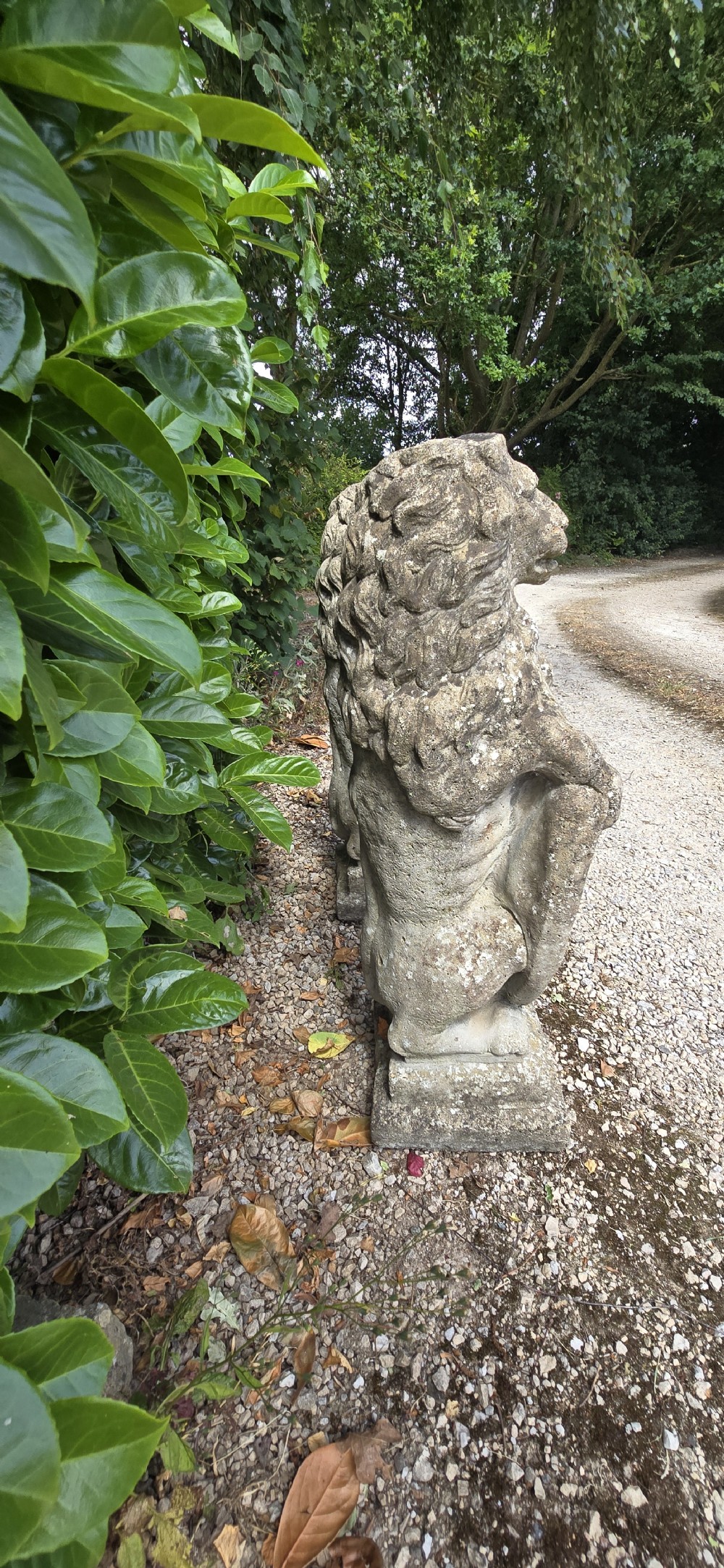 A pair of weathered grey stone garden statues depicting standing lions holding heraldic shields on rectangular bases. View IX