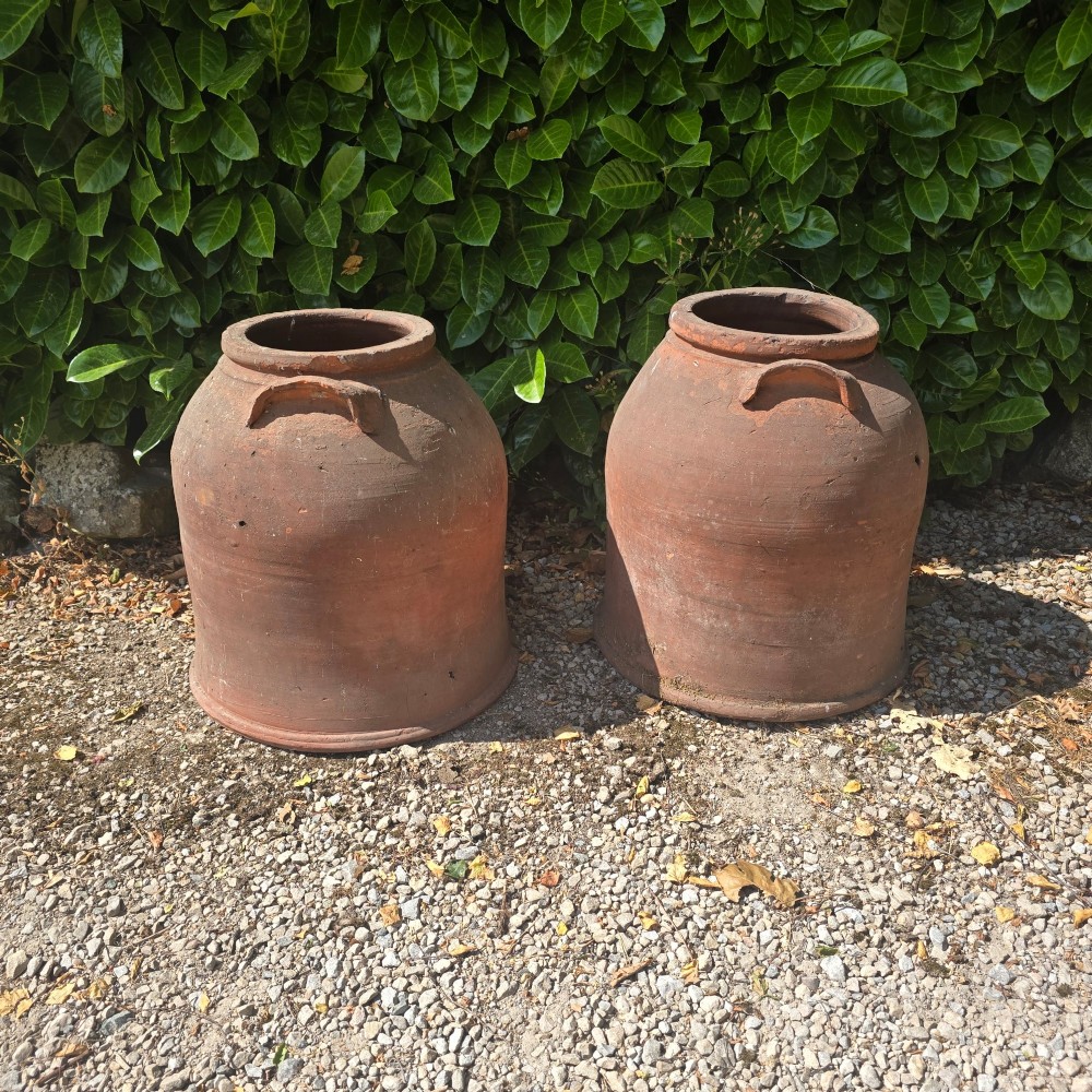 A pair of large Victorian terracotta rhubarb forcers with side handles and an aged clay surface.