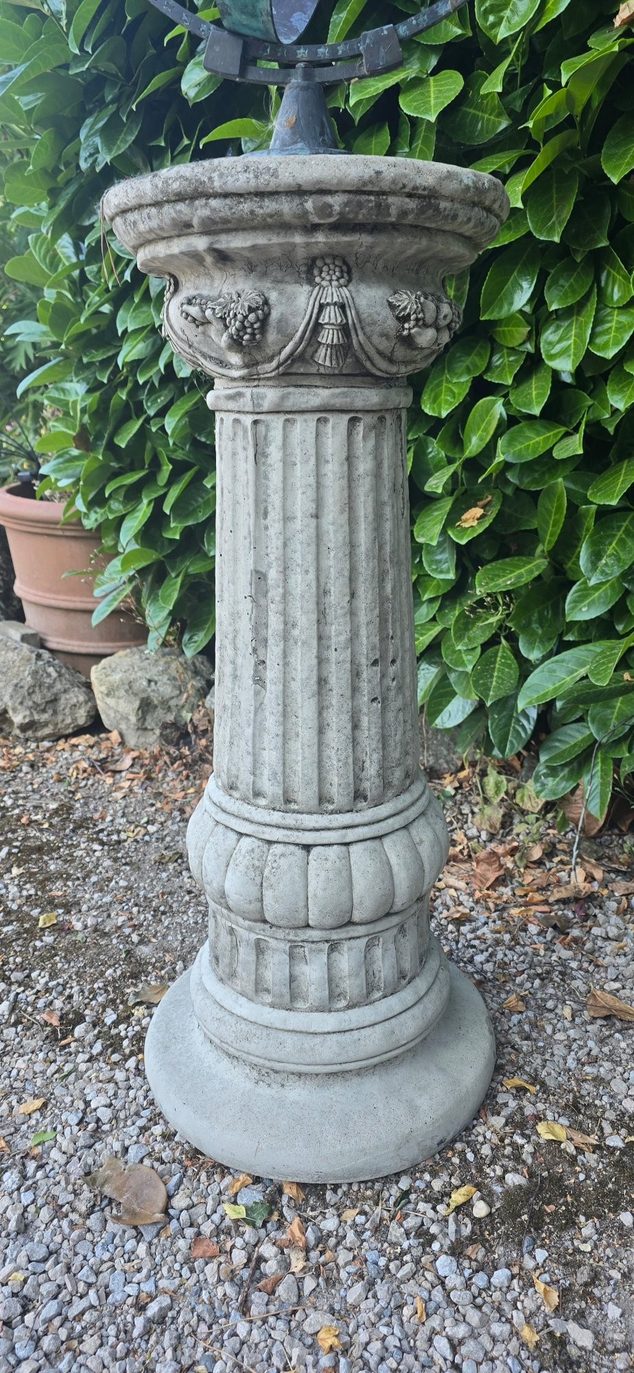 A weathered metal armillary sphere with an arrow gnomon and verdigris patina mounted atop a carved fluted stone pedestal. View V