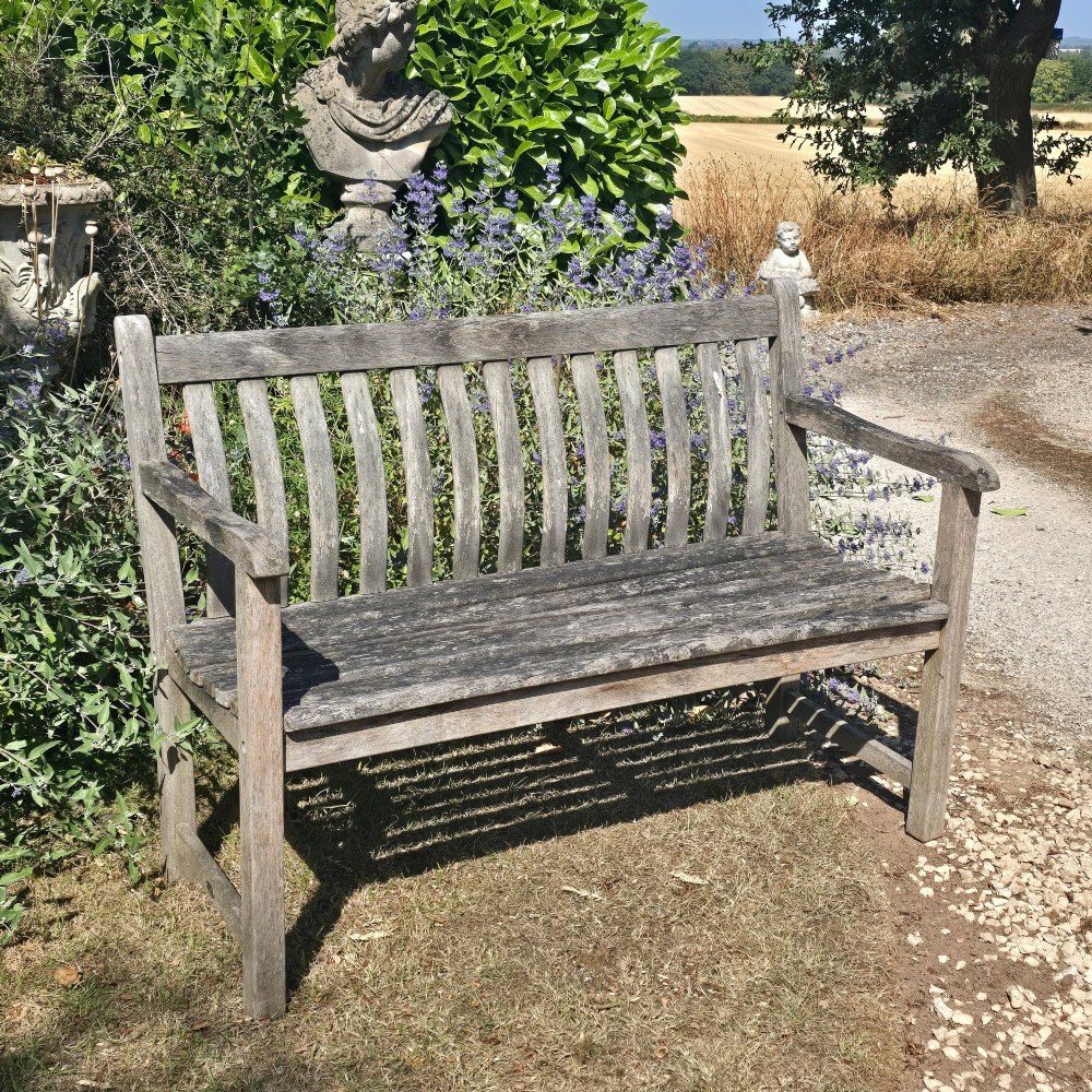 A weathered teak garden bench featuring a vertical slatted backrest, slatted seat, and straight legs connected by stretchers. View II