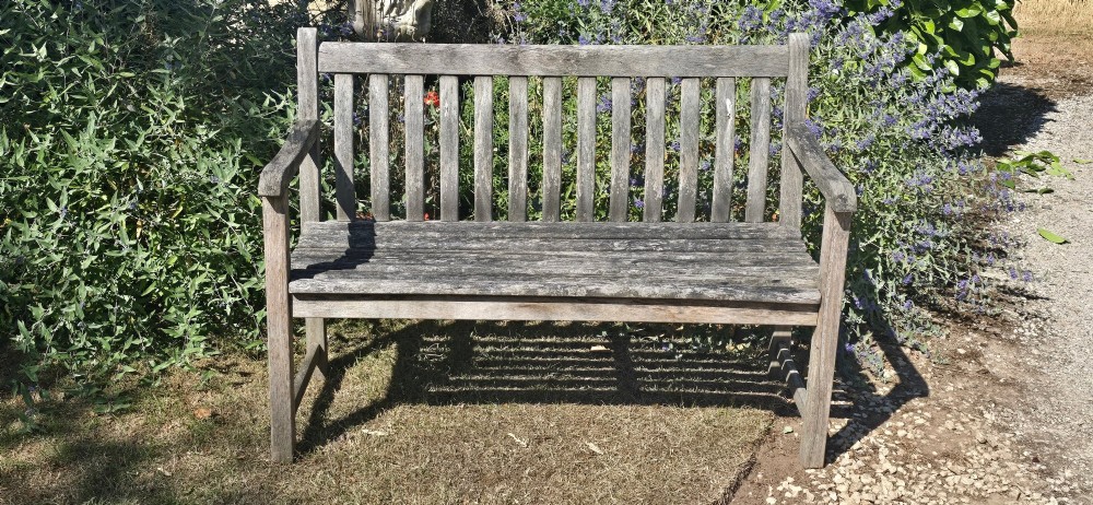 A weathered teak garden bench featuring a vertical slatted backrest, slatted seat, and straight legs connected by stretchers. View III
