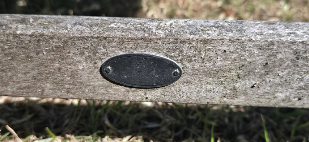 A weathered teak garden bench featuring a vertical slatted backrest, slatted seat, and straight legs connected by stretchers. View VIII
