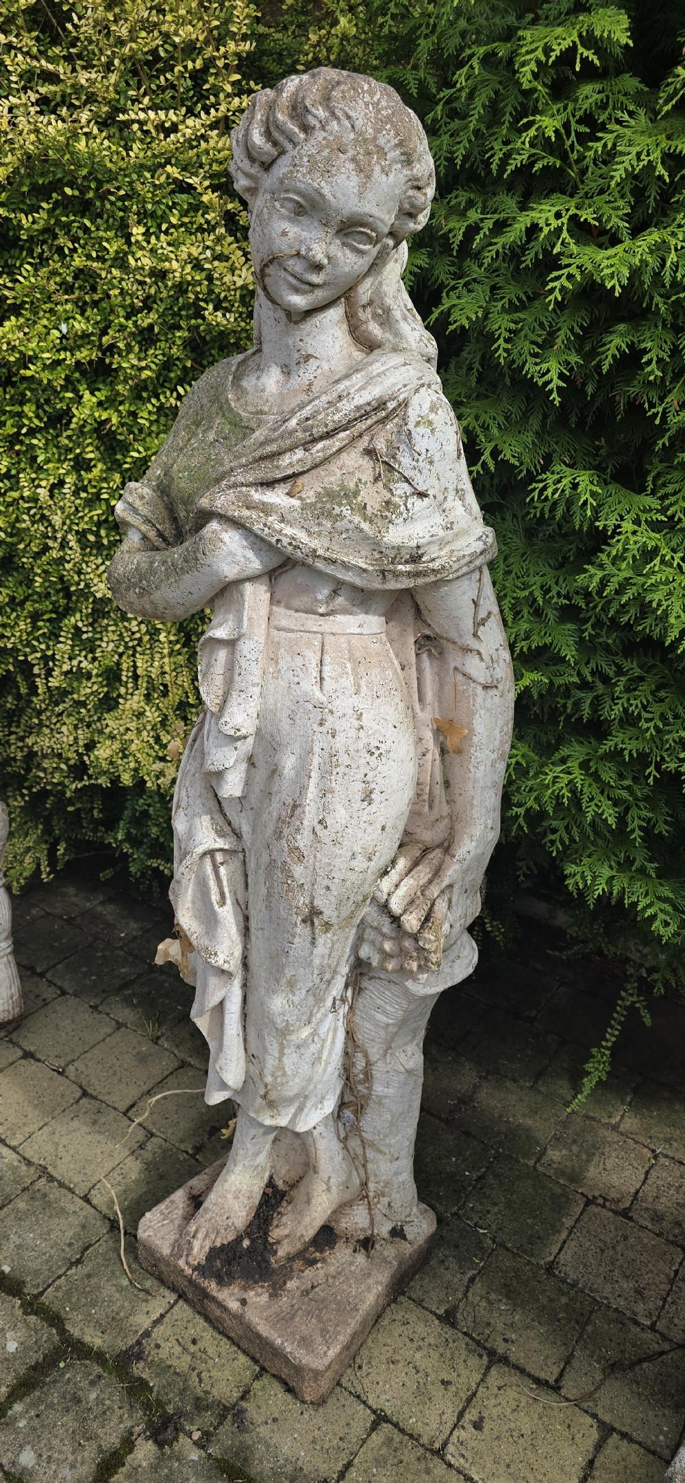 A set of four weathered grey stone full-length classical female statues representing the Four Seasons on rectangular bases. View VII