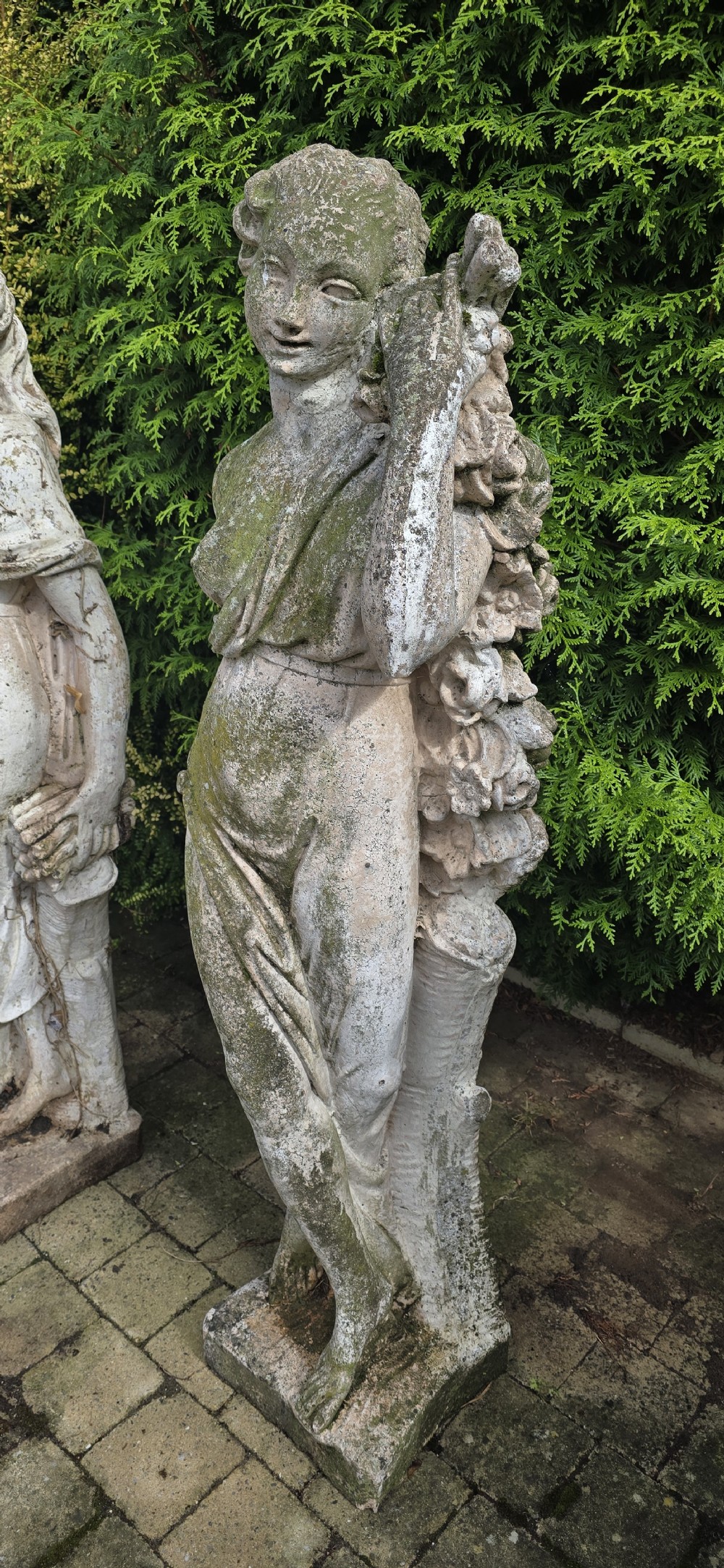 A set of four weathered grey stone full-length classical female statues representing the Four Seasons on rectangular bases. View IX