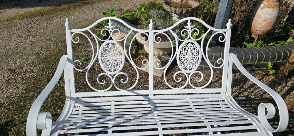 A pair of restored white-painted wrought iron garden rocking benches featuring ornate decorative scrollwork backrests and slatted seats. View VII