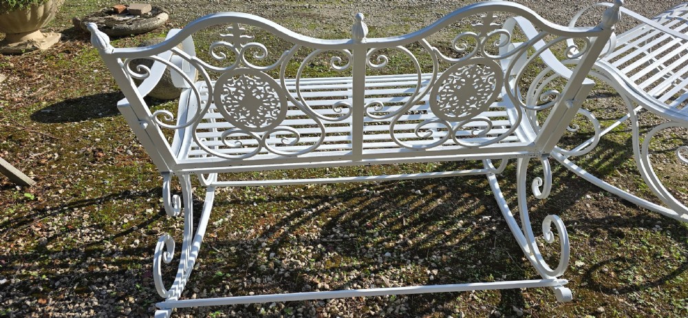 A pair of restored white-painted wrought iron garden rocking benches featuring ornate decorative scrollwork backrests and slatted seats. View XI