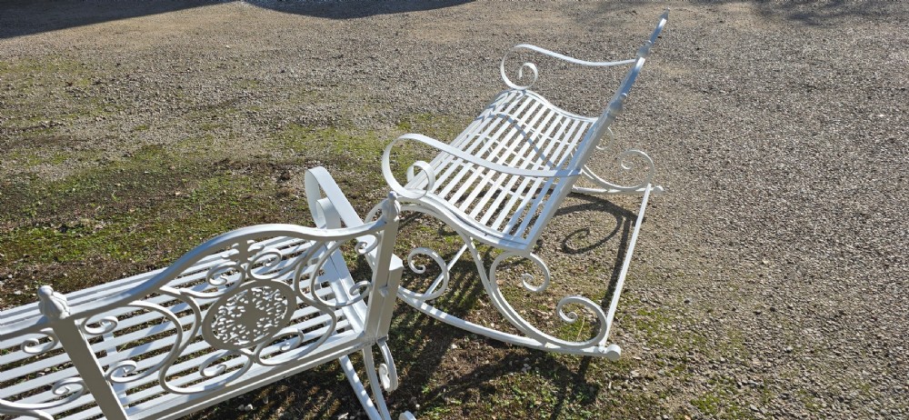 A pair of restored white-painted wrought iron garden rocking benches featuring ornate decorative scrollwork backrests and slatted seats. View XII