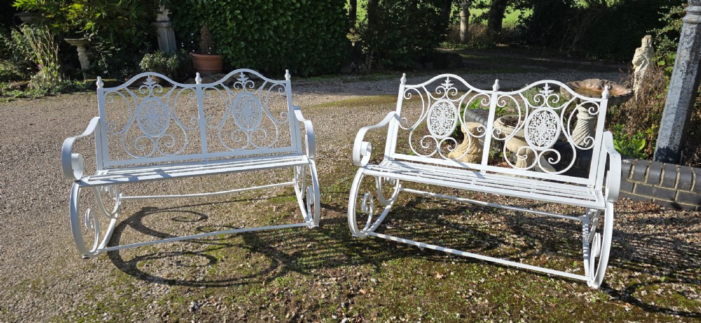 A pair of restored white-painted wrought iron garden rocking benches featuring ornate decorative scrollwork backrests and slatted seats. View XIII