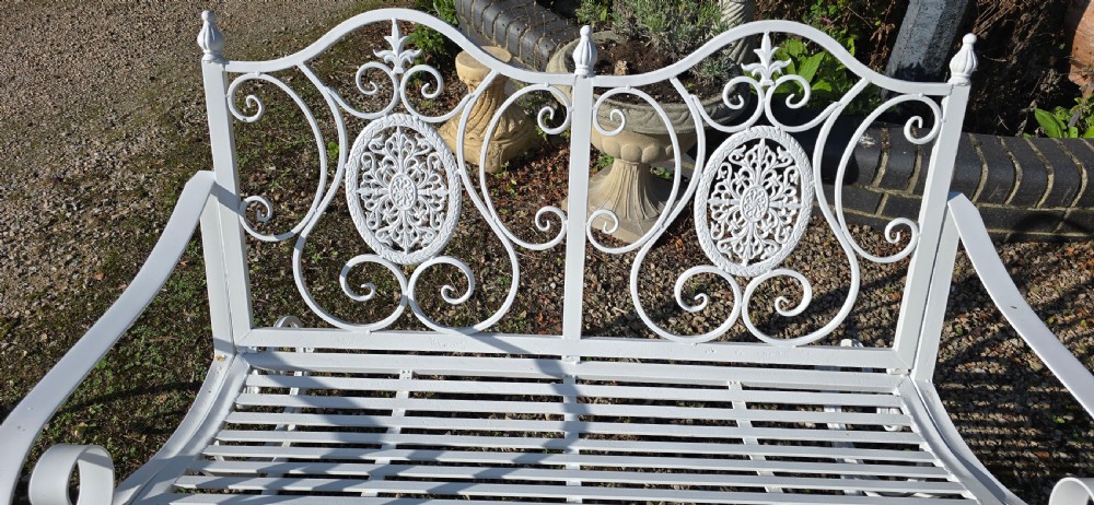 A pair of restored white-painted wrought iron garden rocking benches featuring ornate decorative scrollwork backrests and slatted seats. View XV