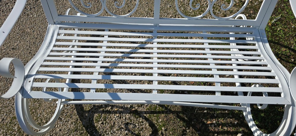 A pair of restored white-painted wrought iron garden rocking benches featuring ornate decorative scrollwork backrests and slatted seats. View XVI