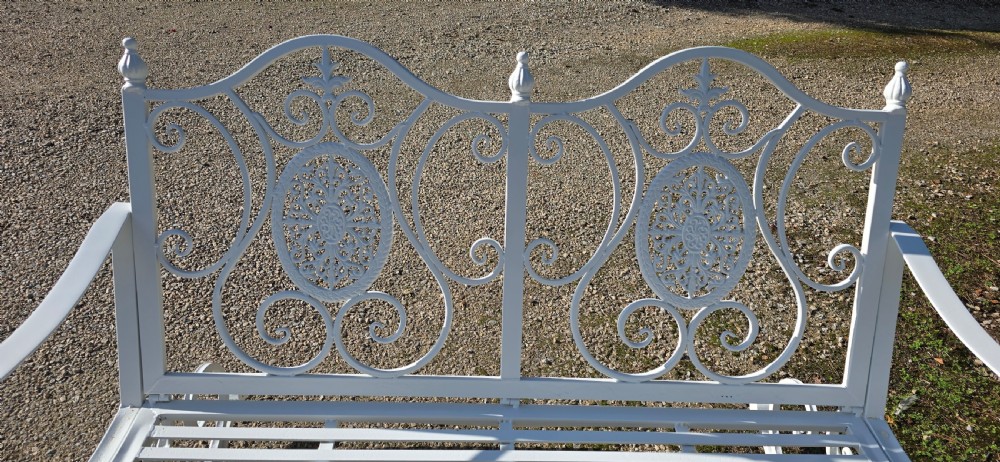 A pair of restored white-painted wrought iron garden rocking benches featuring ornate decorative scrollwork backrests and slatted seats. View XVII