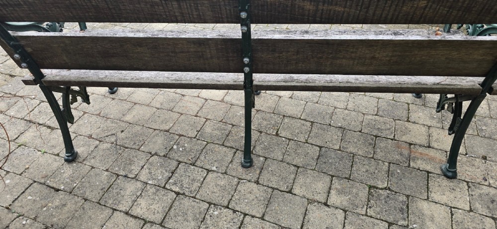 A cast iron garden bench with dark green painted end supports and weathered grey timber slats forming the seat and backrest. View VIII