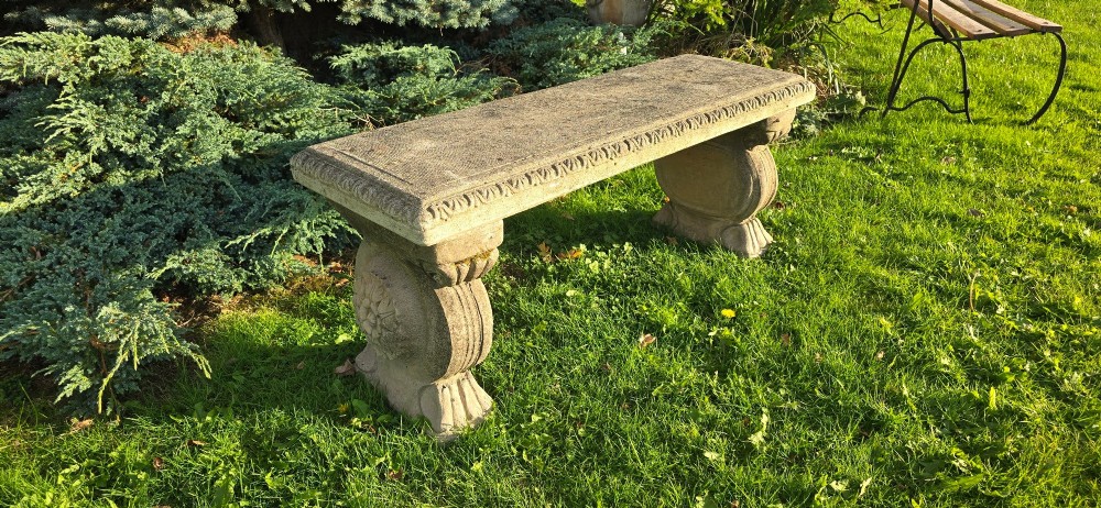 A rectangular weathered stone garden bench featuring carved scroll supports set on lawn grass. View III