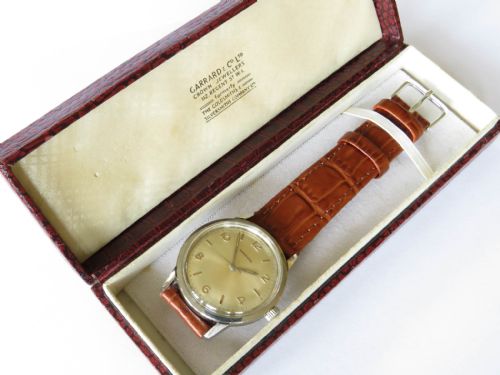 fig 1. A 1960s Garrard gents wristwatch featuring a champagne gold dial with Arabic numerals and a cognac brown leather strap.