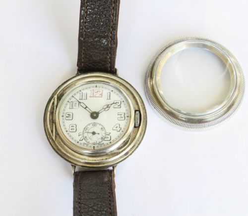 fig 4. A 1930s gentlemans silver hermetic wrist watch with a circular coin-edge bezel, white enamel dial, sub-seconds display, and brown leather strap.