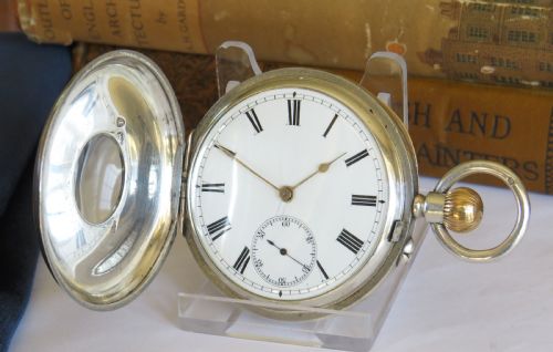 fig 1. A late Victorian sterling silver half hunter pocket watch featuring dark blue enamel Roman numerals on the outer cover and a central glass window.