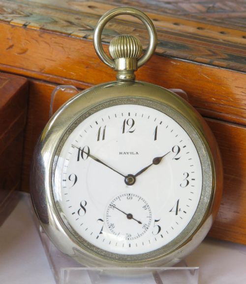 fig 1. An antique open-face silver-toned pocket watch featuring a white enamel dial with black Arabic numerals and a subsidiary seconds dial.