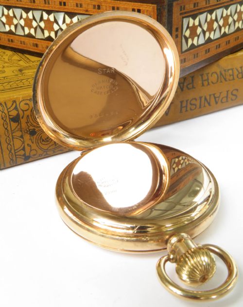 fig 1. An open gold full hunter pocket watch displaying a white enamel dial with black Roman numerals and a subsidiary seconds dial.